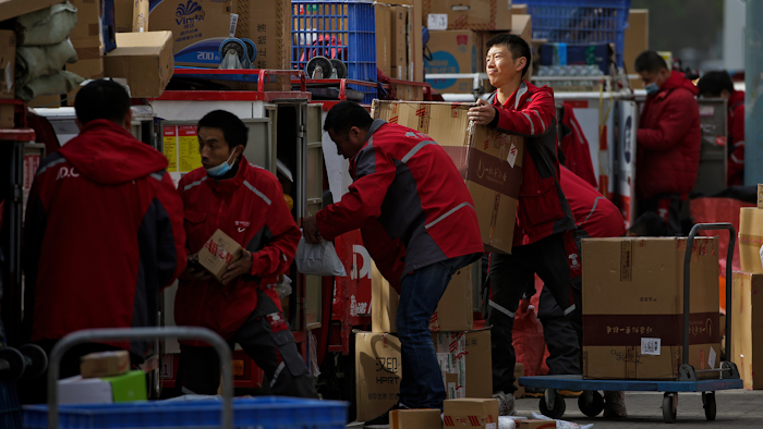 Employees of a private delivery company sort out parcels at a distribution center in Beijing, April 27, 2020.