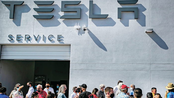 Tesla owners, Tesla employees and local political leaders gather at the service bay doors during an event on Sept. 9, 2021, to celebrate a partnership between Tesla and the Nambé Pueblo after the electric car company repurposed a defunct casino into a sales, service and delivery center near Santa Fe, N.M.