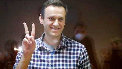 Russian opposition leader Alexei Navalny gestures as he stands in a cage in the Babuskinsky District Court in Moscow, Feb. 20, 2021.