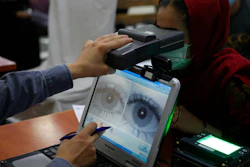 An employee scans the eyes of a woman for biometric data needed to apply for a passport, Kabul, Afghanistan, June 30, 2021.