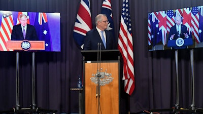 Australian Prime Minister Scott Morrison, center, appears on stage with video links to British Prime Minister Boris Johnson and President Joe Biden, Parliament House, Canberra, Sept. 16, 2021.