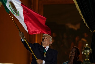 Mexican President Andres Manuel Lopez Obrador waves the national flag after giving the annual independence shout from the balcony of the National Palace, the Zocalo, Mexico City, Sept. 15, 2021.
