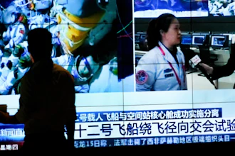 A man watches a TV screen showing CCTV broadcasting Chinese astronauts inside the Shenzhou-12 manned spacecraft, Beijing, Sept. 16, 2021.
