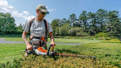 Tyler Campbell uses an electric hedge trimmer at the New York Botanical Garden, the Bronx, New York.