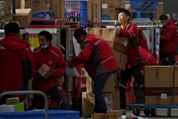 Employees of a private delivery company sort out parcels at a distribution center in Beijing, April 27, 2020.