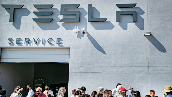 Tesla owners, Tesla employees and local political leaders gather at the service bay doors during an event on Sept. 9, 2021, to celebrate a partnership between Tesla and the Nambé Pueblo after the electric car company repurposed a defunct casino into a sales, service and delivery center near Santa Fe, N.M. Tesla has opened a store on tribal land in New Mexico, sidestepping car dealership laws that prohibit car companies from selling directly to customers.