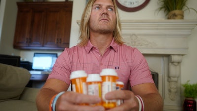 David Stringham holds prescription bottles at his home in Provo, Utah, Aug. 23, 2021.