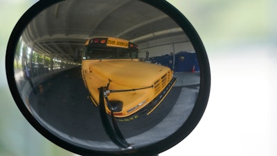 A diesel-powered school bus is reflected in a mirror at MAST Academy, Miami, Sept. 29, 2021.