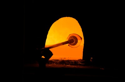 A glass worker heats glass in a methane-powered oven in a factory in Murano island, Venice, Italy, Oct. 7, 2021.