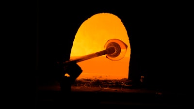 A glass worker heats glass in a methane-powered oven in a factory in Murano island, Venice, Italy, Oct. 7, 2021.