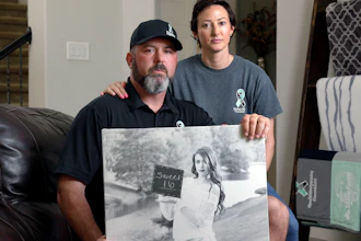 David and Wendy Mills with a photo of their daughter at their home in Spring, Texas, Oct. 12, 2021.