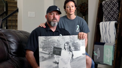 David and Wendy Mills with a photo of their daughter at their home in Spring, Texas, Oct. 12, 2021.