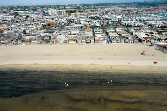 Workers in protective suits clean a contaminated beach in Newport Beach, Calif., Oct.6, 2021.