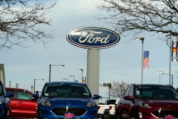 In this Sunday, April 25, 2021, photograph, the blue oval logo of Ford Motor Company is shown over a row of unsold 2021 Escapes at a dealership in east Denver. The global computer chip shortage cut into third-quarter profits at both Ford and crosstown rival General Motors, with both companies having to temporarily close factories, pinching supplies on dealer lots, according to results announced Wednesday, Oct. 27.