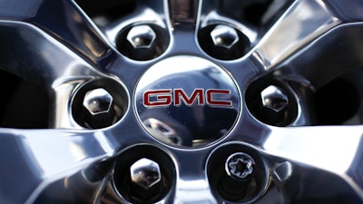 In this April 25, 2017 file, photo, a GMC logo is displayed on the wheel of a truck at a General Motors dealer's lot in Nashville, Tenn. General Motors plans to cash in as the world switches from combustion engines to battery power, promising to double its annual revenue by 2030 with an array of new electric vehicles, profitable gas-powered cars and trucks, and services such as an electronic driving system that can handle most tasks on the road.