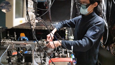 Graduate student Qizhong Liang adjusts JILA's frequency comb breathalyzer, which identifies molecules associated with disease based on colors and amounts of light absorbed inside the tube (left) containing breath samples.