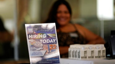 A hiring sign is placed at a booth for prospective employers during a job fair Wednesday, Sept. 22, 2021, in the West Hollywood section of Los Angeles. Workers seeking a new career may face challenges if they’re looking to retrain, labor experts say. That’s because there are few social supports in place that allow career-change aspirants the time and financial help to do it.