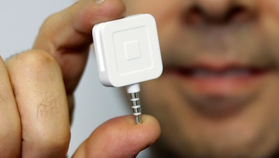 Dr. Greg Werner poses for a picture with his Square credit card reader at his office in New York, Jan. 5, 2015.