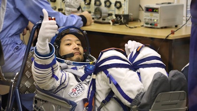 Yozo Hirano gestures during the inspection of his space suit prior to the launch at the Baikonur cosmodrome, Kazakhstan, Dec. 8, 2021.
