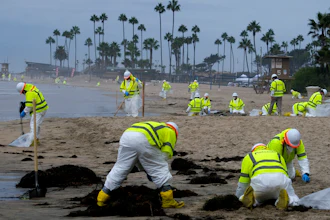 Workers in protective suits clean the contaminated beach in Corona Del Mar after an oil spill off the Southern California coast, Oct. 7, 2021.