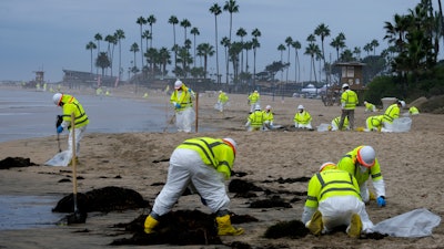 Workers in protective suits clean the contaminated beach in Corona Del Mar after an oil spill off the Southern California coast, Oct. 7, 2021.