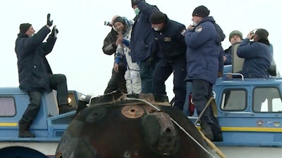 A Russian space agency rescue team helps Yusaku Maezawa depart the capsule shortly after landing, Dec. 20, 2021.