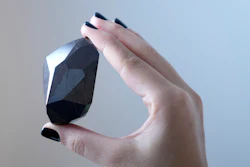 An employee of Sotheby's Dubai presents a 555.55 Carat Black Diamond 'The Enigma' to be auctioned at Sotheby's Dubai gallery, in Dubai, United Arab Emirates, Monday, Jan. 17, 2022.