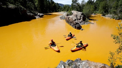 People kayak in water colored from a mine waste spill at the Animas River near Durango, Colo., Aug. 6, 2015.