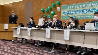 Flanked by other lawyers, a plaintiff and the mother of another, lawyer Yuichi Kaido, third from left, shows a court document during a news conference, Tokyo, Jan. 27, 2022.