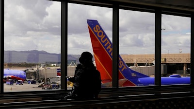 A passenger walks past a Southwest Airlines plane at Sky Harbor International Airport in Phoenix, March 26, 2021. AT&T and Verizon have agreed to delay the launch of a new slice of 5G service by two weeks after airlines and the nation's aviation regulator complained about potential interference with systems on board planes.