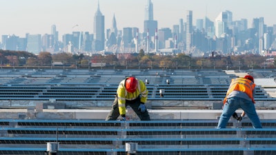 Electricians with IBEW Local 3 install solar panels on top of the Terminal B garage at LaGuardia Airport, New York, Nov. 9, 2021.