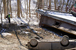 An investigator looks at the bus and a vehicle after a bridge collapse in Pittsburgh, Jan. 29, 2022.
