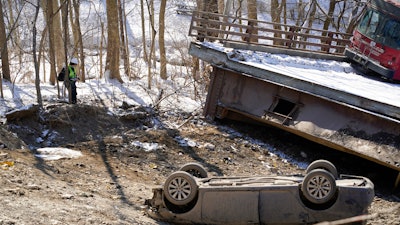 An investigator looks at the bus and a vehicle after a bridge collapse in Pittsburgh, Jan. 29, 2022.