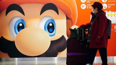 A traveler walks past an ad featuring a Nintendo character at Narita airport near Tokyo, Jan. 23, 2020.