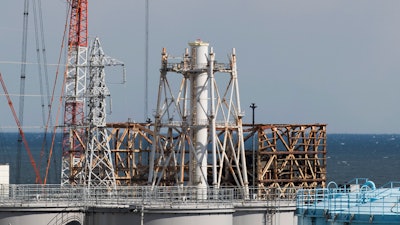 The damaged Unit 1 reactor, back, and the exhaust stack shared with the Unit 1 and 2 reactors at the Fukushima Daiichi nuclear power plant, Okuma town, Japan, Feb. 27, 2021.