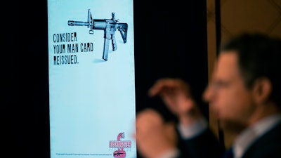 An ad for an AR-15-style rifle is displayed while attorney Josh Koskoff speaks during a news conference, Trumbull, Conn., Feb. 15, 2022.