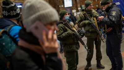 Ukrainian soldiers stand guard as people try to leave at the Kyiv train station, Feb. 24, 2022.
