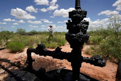 Ashley Williams Watt walks near a wellhead and flowline at her ranch, Friday, July 9, 2021, near Crane, Texas. The wells on Watt's property seem to be unplugging themselves. Some are leaking dangerous chemicals into the ground, which are seeping into her cattle's drinking water. And she doesn't know how long it's been going on.