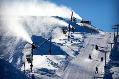 Snowmaking machines spray artificially made snow on a ski slope during a test ahead of the 2022 Winter Olympics.