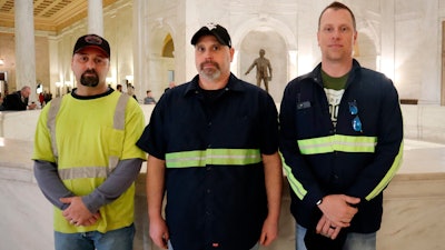 Coal miners Jason Stewart, Tim Richmond and Cory Lyseski pose for a photo at the West Virginia state Capitol, March 1, 2022.