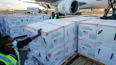 An airport worker stands next to boxes of Moderna coronavirus vaccines donated by the U.S. government, Nairobi, Kenya, Aug. 23, 2021.