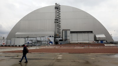 A man walks past a shelter covering the exploded reactor at the Chernobyl nuclear plant, Chernobyl, Ukraine, April 15, 2021.