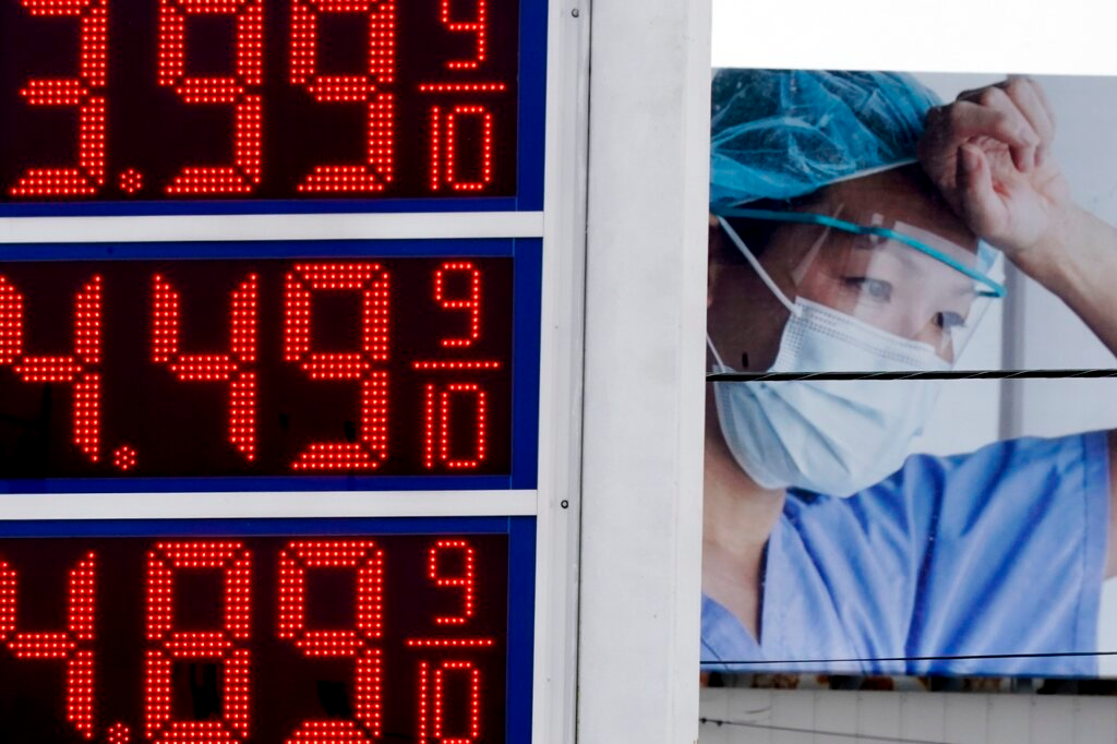 Prices are displayed on a sign at a gas station in Milwaukee on March 14, 2022, with a billboard for medical services in the background.