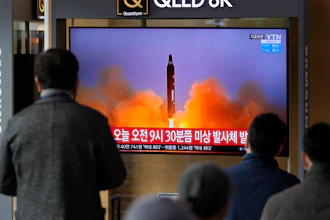 People watch a TV screen showing a news program reporting about North Korea's missile with file footage, Seoul, March 16, 2022.