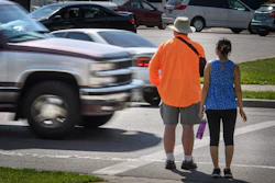 A truck drives through a crosswalk in front of pedestrian volunteers Dave Passiuk and Nelsie Yang, St. Paul, Minn., June 8, 2016.