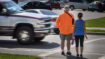 A truck drives through a crosswalk in front of pedestrian volunteers Dave Passiuk and Nelsie Yang, St. Paul, Minn., June 8, 2016.