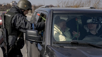 A Ukrainian police officer offer tulips to female travelers at a checkpoint on the outskirts of Kyiv, March 20, 2022.