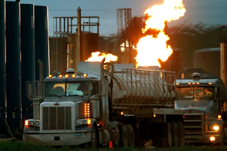 Tanker trucks line up near a natural gas burn-off, Williston, N.D., June 9, 2014.