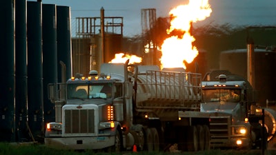 Tanker trucks line up near a natural gas burn-off, Williston, N.D., June 9, 2014.
