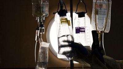 A nurse checks on IV fluids while talking to a COVID-19 patient at Providence Holy Cross Medical Center, Los Angeles, Dec. 13, 2021.